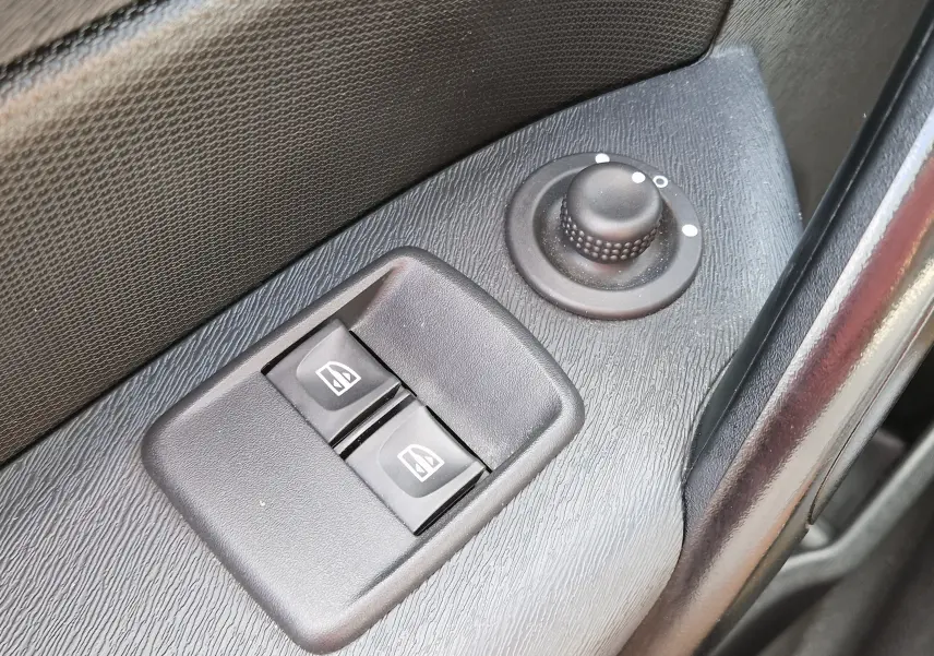 Gros plan sur les commandes de lève-vitres et réglage des rétroviseurs côté conducteur du Renault Kangoo blanc 2021.