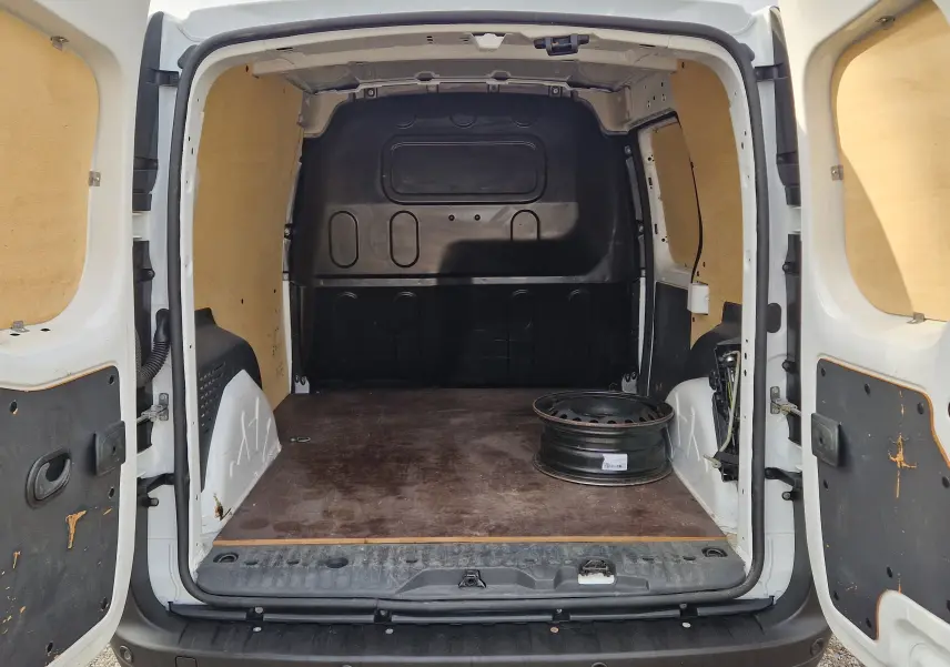 Vue arrière ouverte du Renault Kangoo blanc 2021, montrant l'espace de chargement vide avec un seul jante métallique posée au sol.