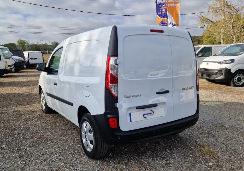 Vue 3/4 arrière droite d’un Renault Kangoo blanc utilitaire avec hayon fermé sur un parking extérieur.
