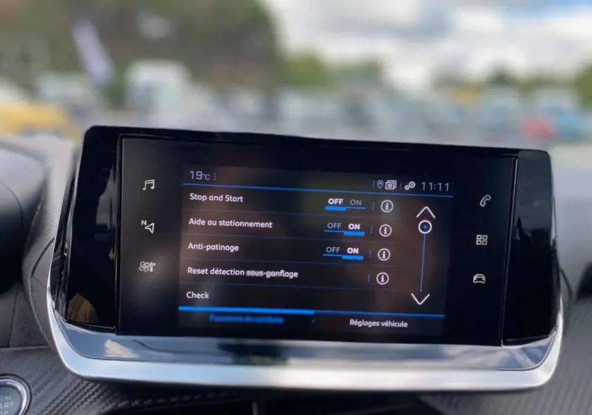 Écran tactile central de la Peugeot 208 noir affichant les réglages d'aide à la conduite en intérieur.