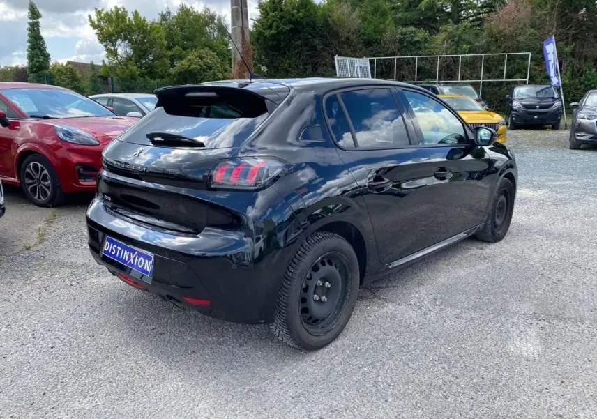 Peugeot 208 noire vue en 3/4 arrière droit sur parking, avec feux arrière à griffes et jantes tôles noires.