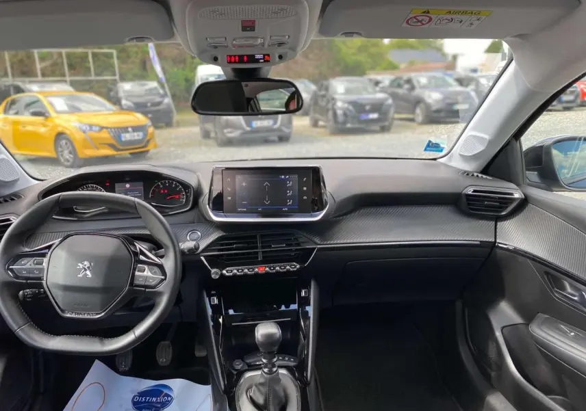 Intérieur noir de la Peugeot 208 2021, vue de face sur le tableau de bord avec écran tactile et volant multifonctions.