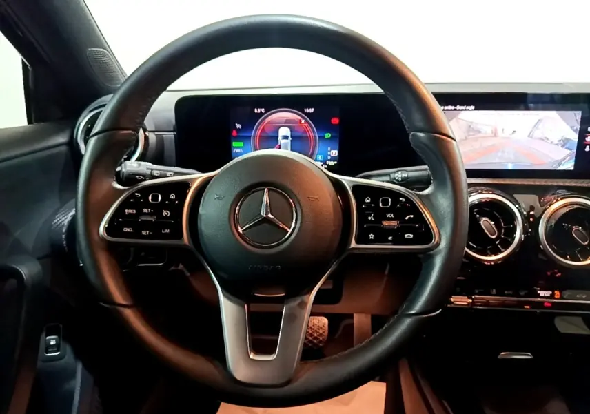 Vue intérieure centrée sur le volant cuir noir et le tableau de bord numérique de la Mercedes Classe A 250 e Business Line.