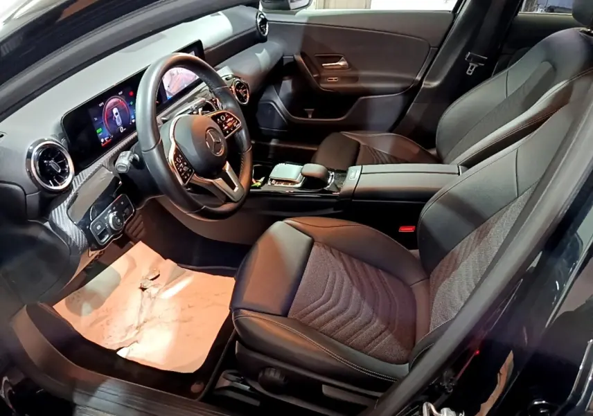 Vue intérieure côté conducteur de la Mercedes Classe A 250 e Business Line noire, avec tableau de bord digital et sièges en cuir.