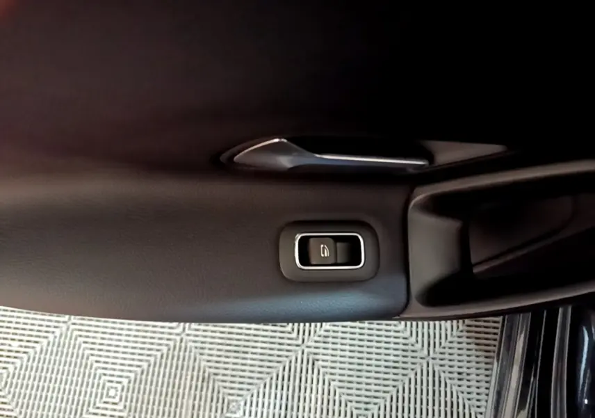 Gros plan sur la poignée intérieure et le bouton de verrouillage de la porte côté gauche d’une Mercedes Classe A noire.