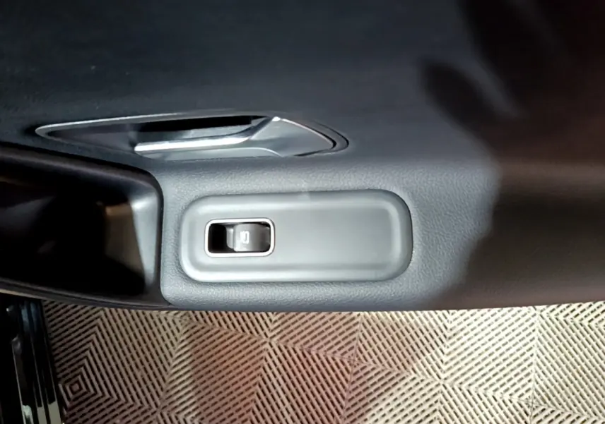 Gros plan sur le bouton de verrouillage des portes intégré dans la garniture intérieure noire d'une Mercedes Classe A 250 e.