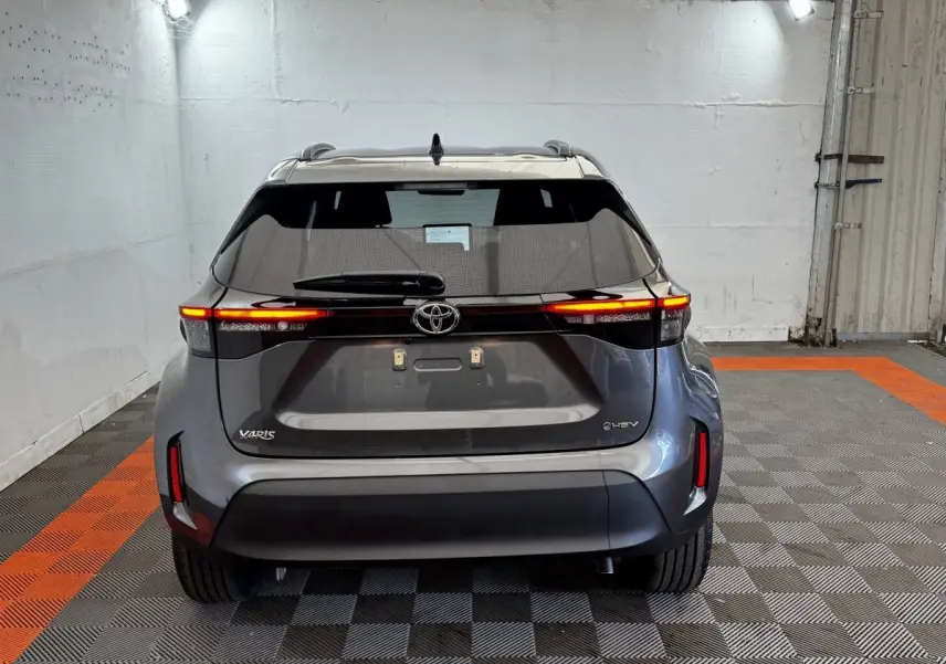 Vue arrière d'une Toyota Yaris Cross gris foncé avec feux LED allumés dans un garage éclairé.