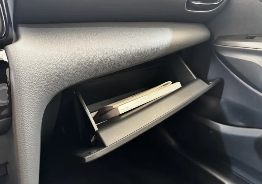 Gant de boîte à gants ouvert côté passager dans l’habitacle gris foncé du Toyota Yaris Cross 2026.