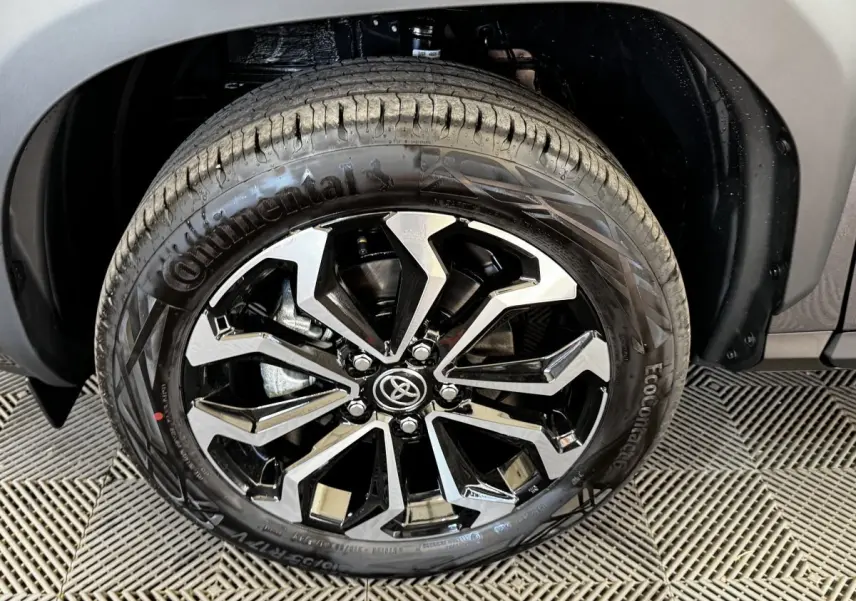 Gros plan sur la roue avant droite d’une Toyota Yaris Cross gris foncé, jante alliage noire et argentée distinctive.