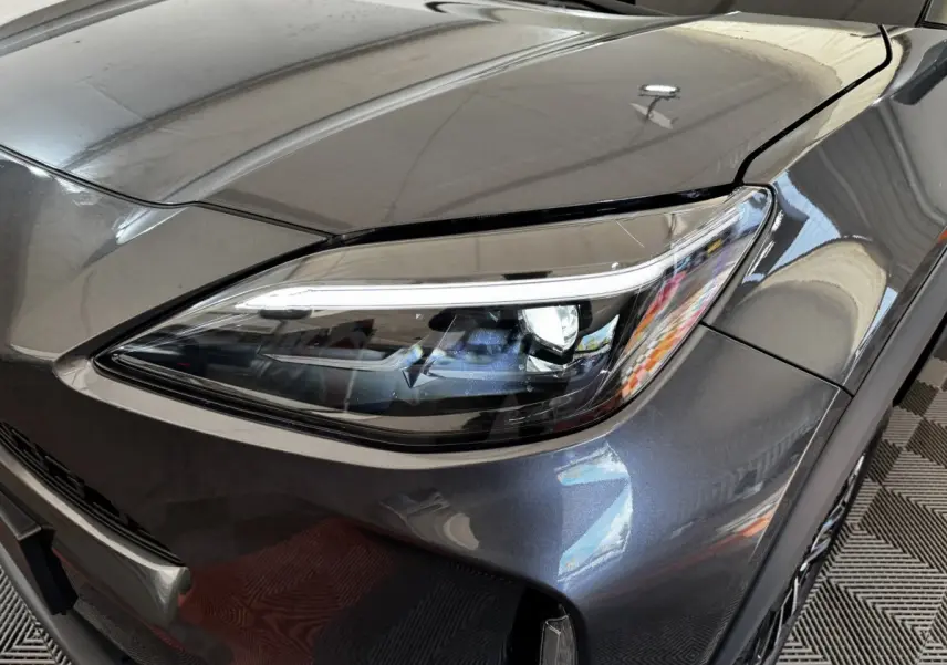 Gros plan sur le phare avant droit du Toyota Yaris Cross gris foncé, mettant en valeur son design LED moderne.