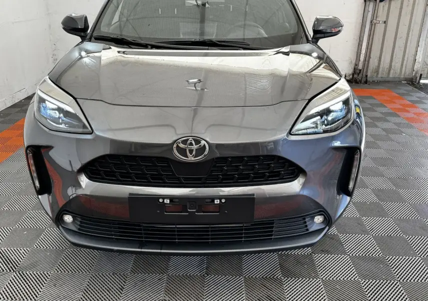 Vue frontale d'une Toyota Yaris Cross 1.5 Hybrid 130h Design Auto gris foncé avec phares LED et calandre noire.