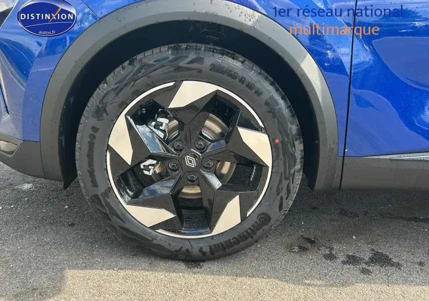 Gros plan sur la roue avant gauche avec jante alu noire et argent du Renault Captur bleu iron 2025.