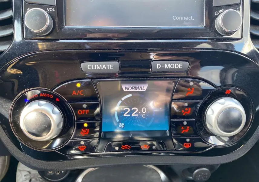 Vue rapprochée de la console centrale du Nissan Juke blanc 2017, affichant la climatisation automatique à 22°C.