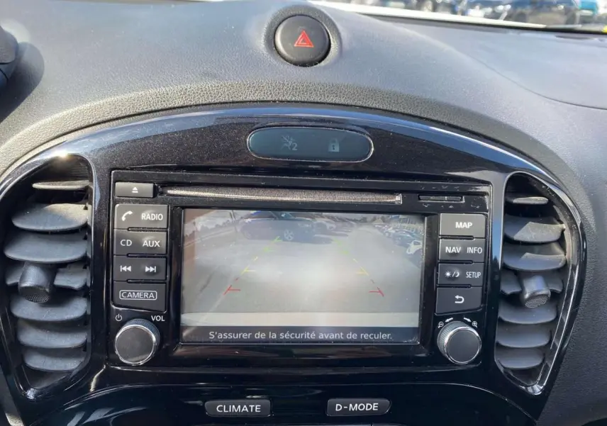 Vue rapprochée de l'écran central noir du Nissan Juke blanc 2017 affichant la caméra de recul et les commandes multimédia.