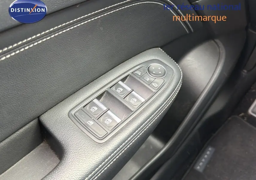 Gros plan sur la commande des vitres électriques côté conducteur en cuir noir avec surpiqûres blanches du Renault Arkana gris.