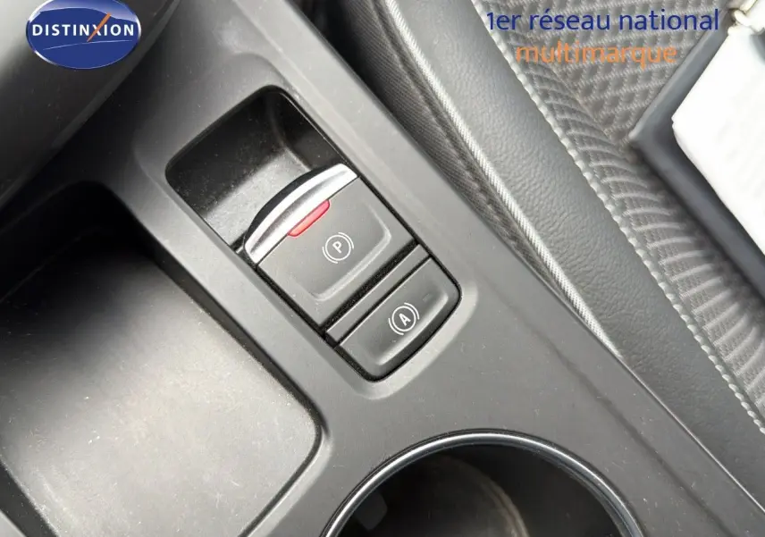 Gros plan sur la console centrale noire du Renault Arkana gris, montrant les boutons de frein à main électrique et d'arrêt automatique.