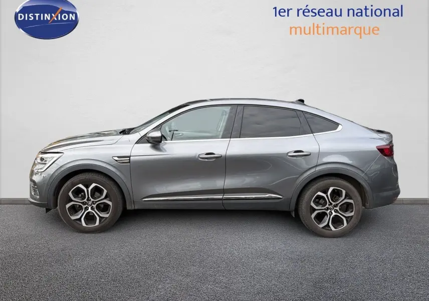 Profil côté gauche d'une Renault Arkana gris métallisé 2022 avec jantes alliage bicolores et lignes fluides.