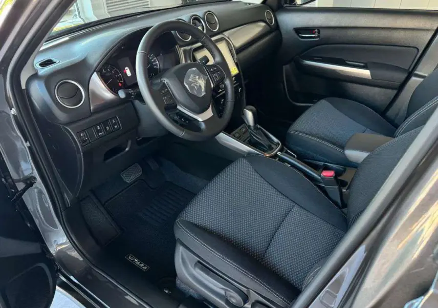 Intérieur avant droit du Suzuki Vitara 2025 gris silky silver, avec volant multifonction et console centrale automatique.