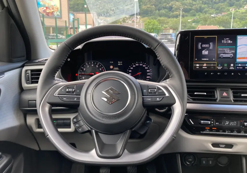 Volant cuir multifonctions Suzuki Swift 2025 avec tableau de bord numérique et écran tactile central affichant navigation et radio.