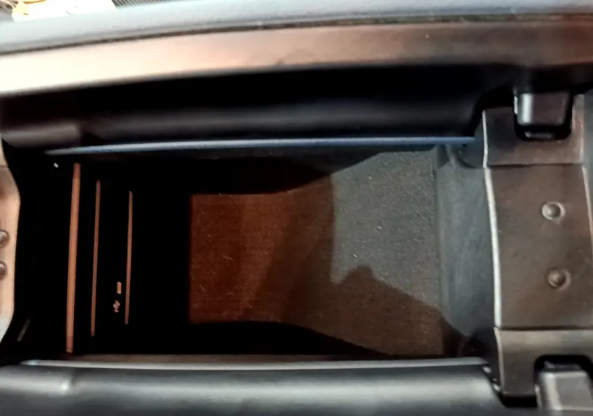Vue en plongée de la console centrale ouverte d'une Mercedes Classe A gris clair, montrant un espace de rangement intérieur.