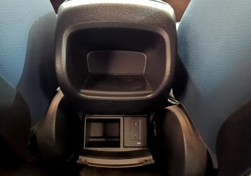 Vue rapprochée de la console arrière noire entre les sièges avant d’une Mercedes Classe A gris clair.