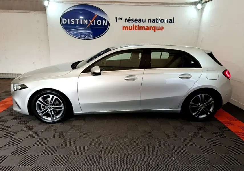 Vue de profil côté gauche d'une Mercedes Classe A A 180 d Business Line gris clair dans un showroom intérieur.