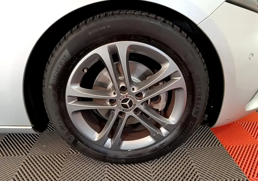 Gros plan sur la roue avant gauche gris clair d'une Mercedes Classe A 180 d Business Line 2020 avec jante alliage et logo Mercedes.