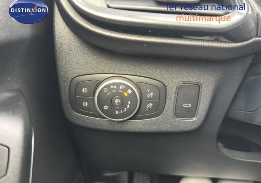 Gros plan sur le bouton de commande des feux et ouverture du coffre dans l’habitacle noir du Ford Puma blanc 2020.