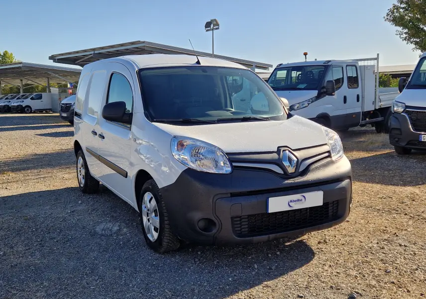 Renault Kangoo blanc vue 3/4 avant droit avec pare-chocs noir mat sur un parking en extérieur.