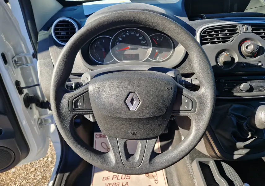 Vue intérieure centrée sur le volant noir du Renault Kangoo blanc 2021 avec tableau de bord et commandes visibles.