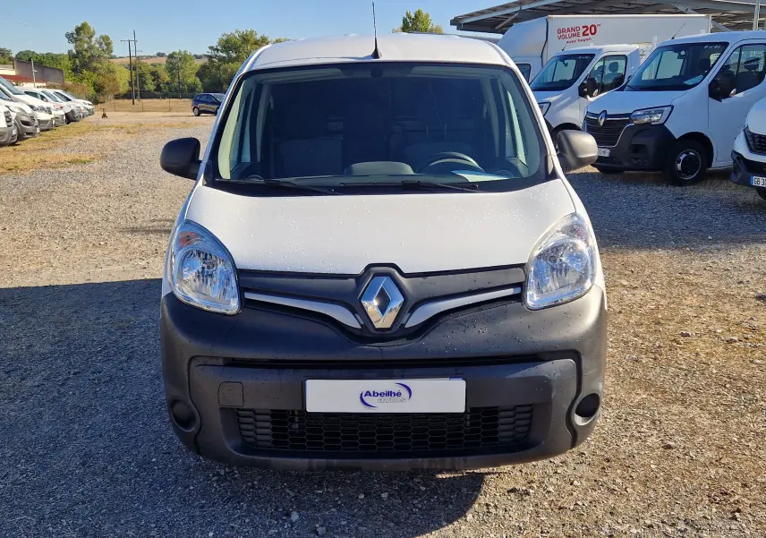 Vue avant d'un Renault Kangoo blanc 2021 avec pare-chocs noir mat, stationné sur un terrain gravillonné en extérieur.