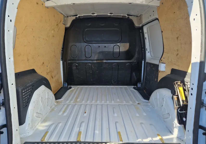 Vue intérieure arrière du coffre blanc du Renault Kangoo 1.5 Blue dCi 80 Extra, montrant un espace utilitaire vide avec parois en bois.