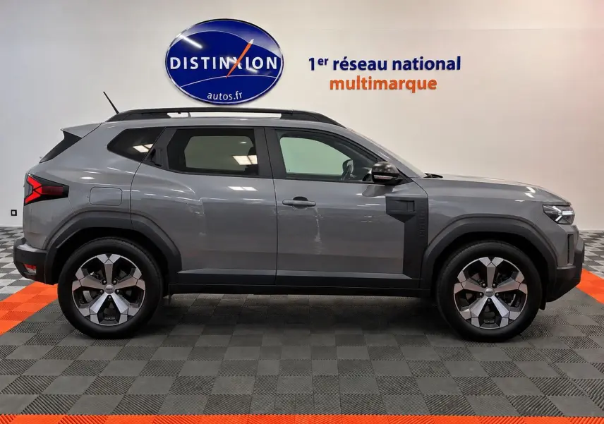 Profil latéral droit du Dacia Duster 2026 gris schiste avec jantes alliage et détails noirs contrastants.