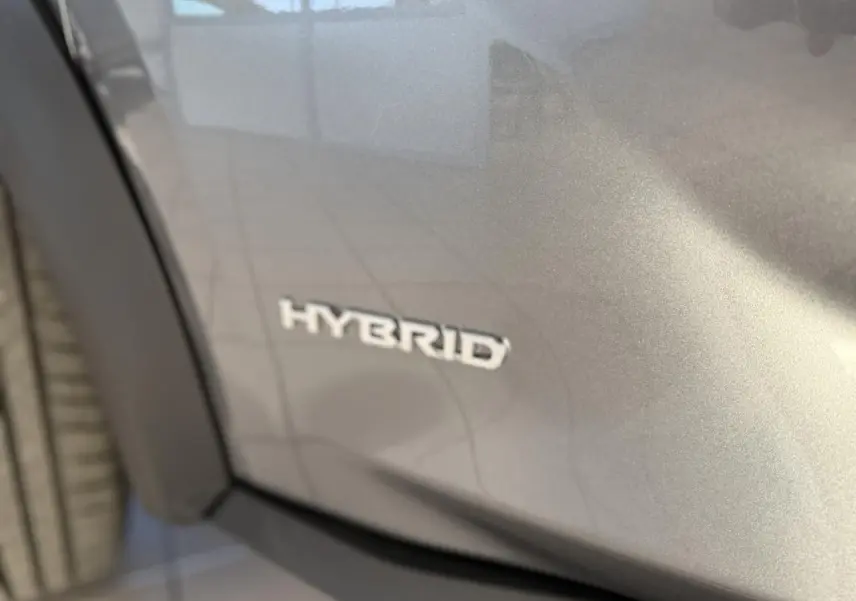 Gros plan sur l’inscription Hybrid sur la portière côté gauche d’un Nissan Juke gris métallisé 2024.