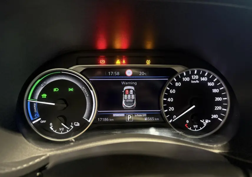 Tableau de bord du Nissan Juke Hybrid 2024 montrant les compteurs et un avertissement de porte ouverte.