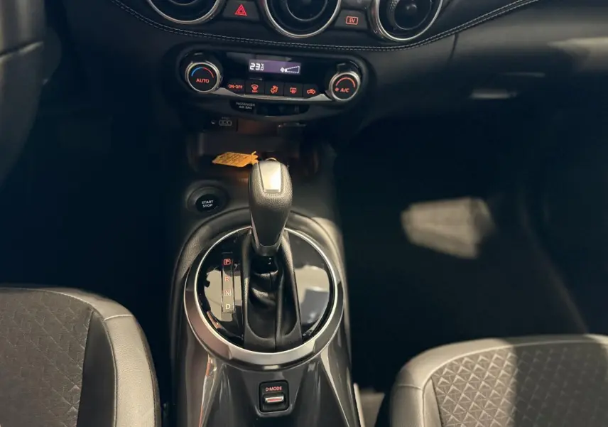 Intérieur du Nissan Juke Hybrid 2024, vue rapprochée sur levier de vitesses automatique et console centrale noire.