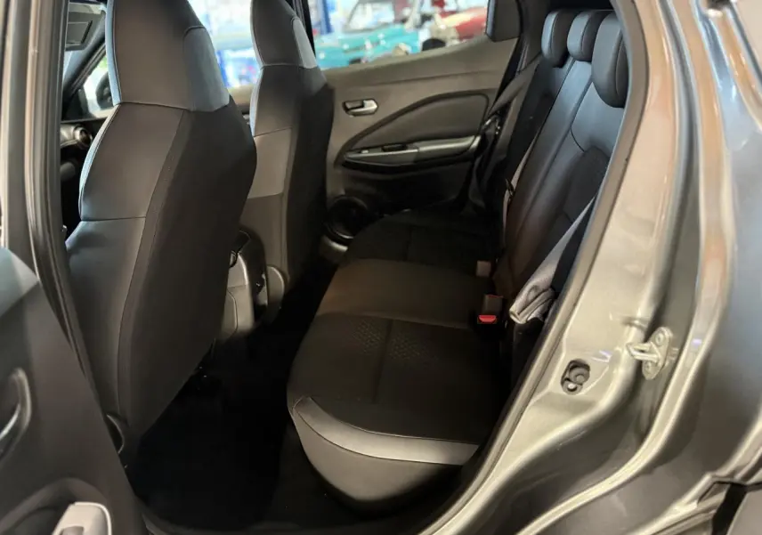 Vue intérieure côté arrière droit du Nissan Juke Hybrid 143 N-Connecta gris métallisé, montrant la banquette arrière en tissu noir.
