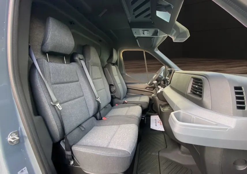 Vue intérieure côté gauche du Renault Master 2025, montrant la banquette passager grise avec surpiqûres bleues et tableau de bord gris.