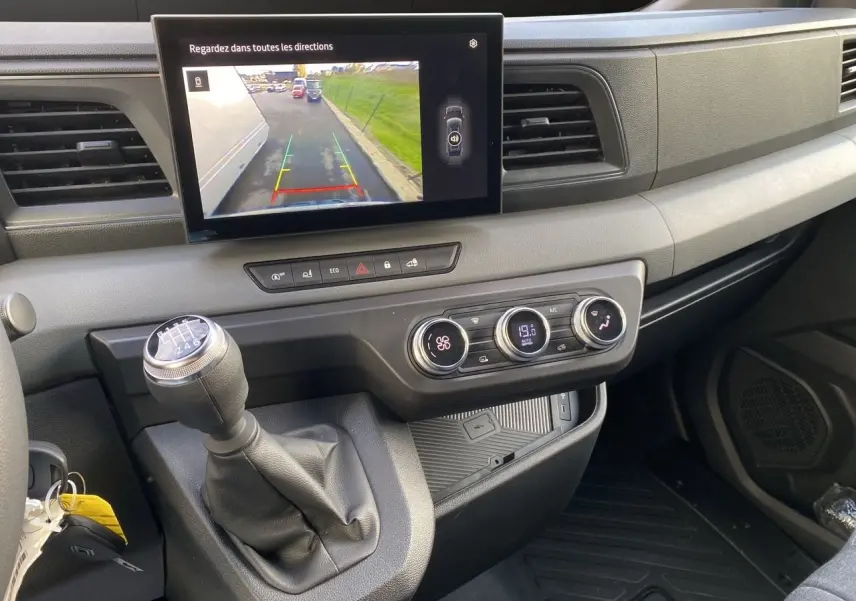 Vue intérieure du tableau de bord du Renault Master 2025 avec écran de caméra de recul et levier de vitesse manuel.