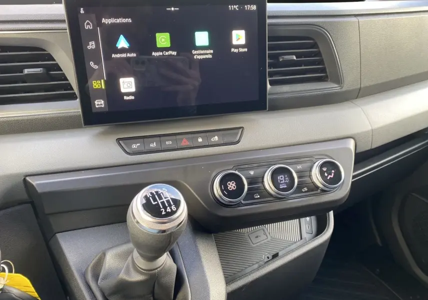Vue rapprochée du tableau de bord du Renault Master 2025 avec écran tactile, climatisation et levier de vitesse manuel.