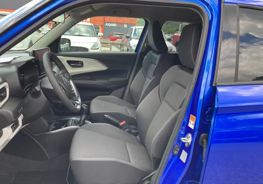 Intérieur de la Suzuki Swift 2025 en bleu Frontier, vue côté gauche montrant sièges tissu et volant cuir multifonctions.