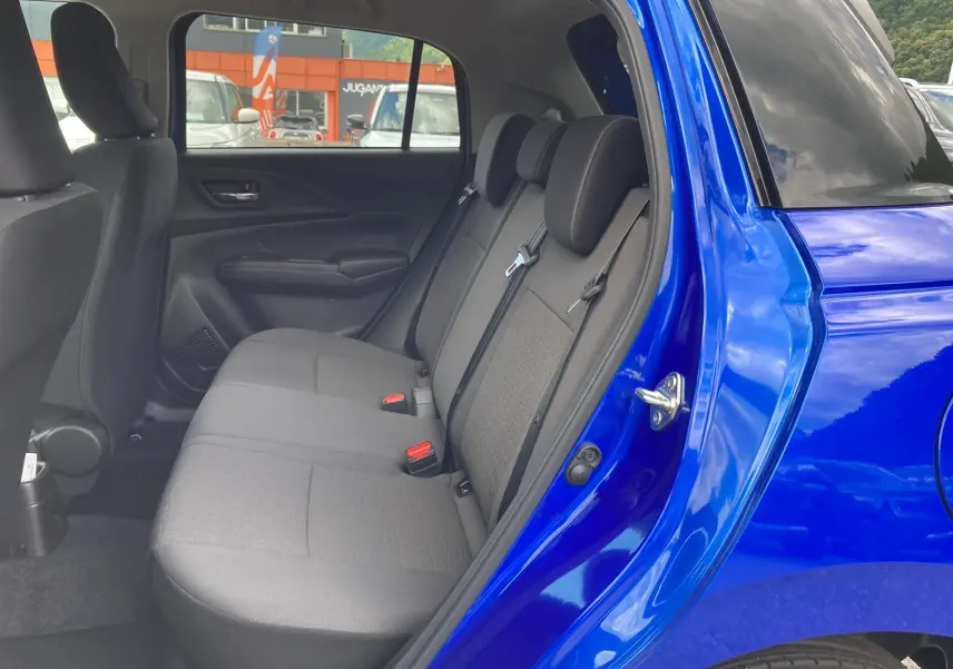Vue intérieure côté arrière gauche sur les sièges arrière en tissu gris d'une Suzuki Swift Frontier blue pearl 2025.