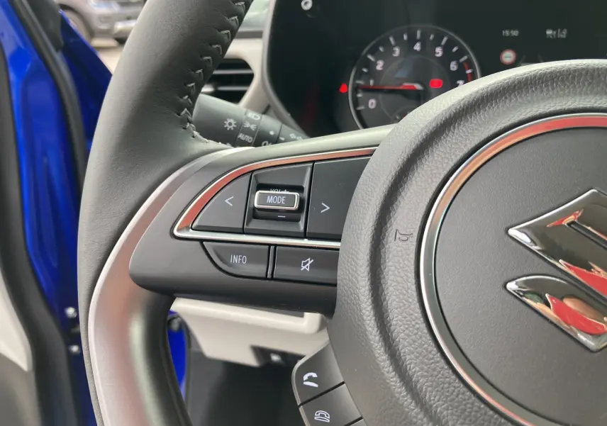 Gros plan sur le volant cuir multifonctions de la Suzuki Swift Frontier Blue Pearl avec commandes audio et téléphone.