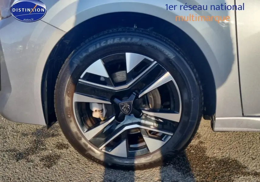 Gros plan sur la jante alu noire et argentée du côté arrière droit d'une Peugeot 208 gris artense.