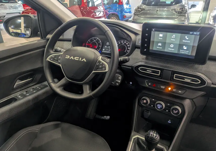 Vue intérieure côté conducteur du tableau de bord de la Dacia Sandero TCe 90 gris avec écran tactile et boîte manuelle.