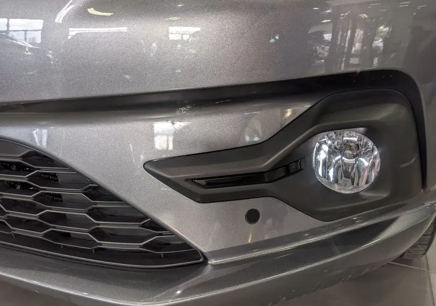 Gros plan sur le pare-chocs avant droit gris schiste de la Dacia Sandero TCe 90 CH Journey avec antibrouillard intégré.