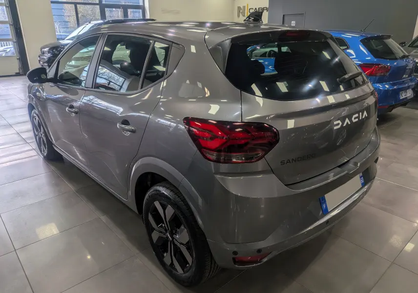 Vue 3/4 arrière droite d'une Dacia Sandero TCe 90 gris schiste avec feux arrière LED et jantes alliage noires.