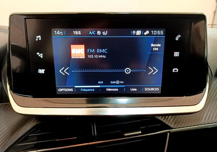 Écran tactile central du tableau de bord du Peugeot 2008 blanc, affichant la radio FM RMC à 103,10 MHz.
