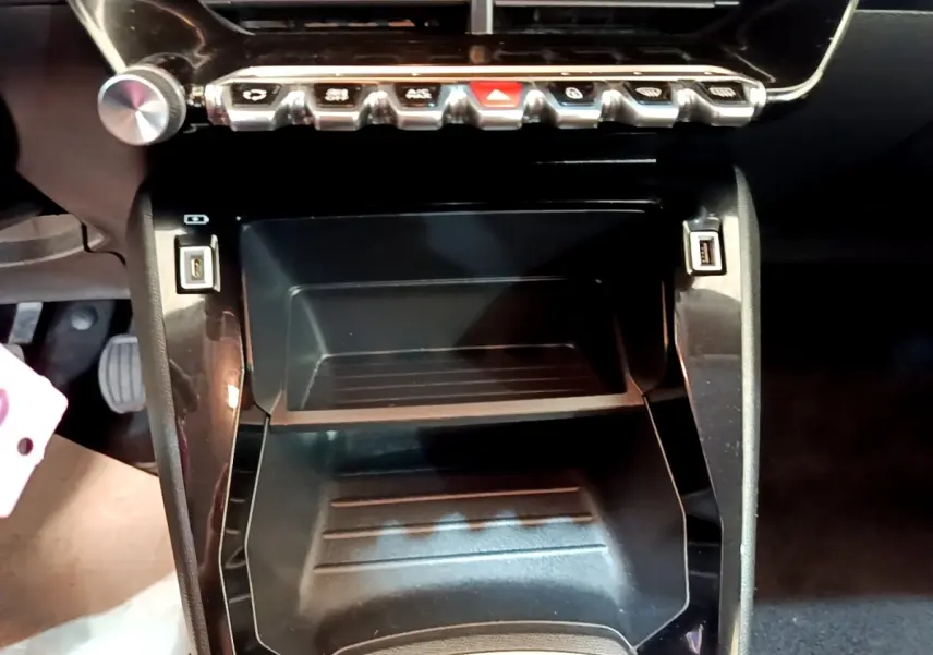 Gros plan sur la console centrale noire du Peugeot 2008 2021 avec boutons de commande et ports USB visibles.