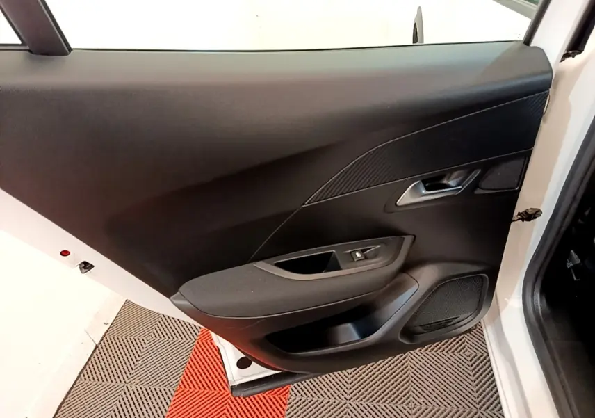 Vue rapprochée de la porte avant gauche blanche d’un Peugeot 2008 2021 avec garniture noire et commande de vitre.